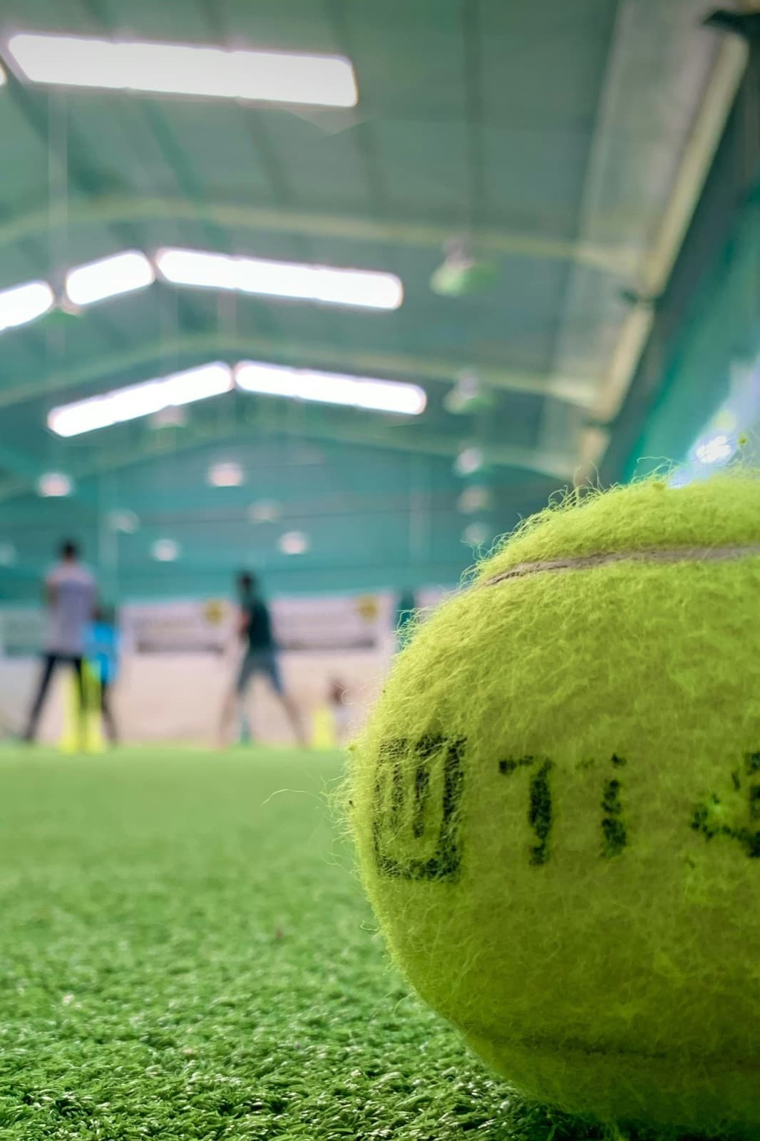 A soft ball on indoor turf with players training behind