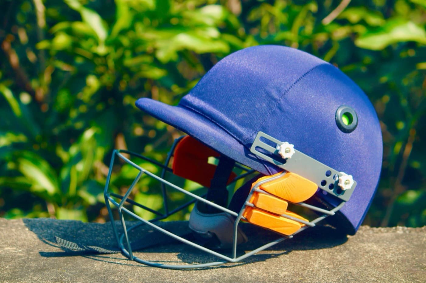 A navy cricket helmet with a face grille